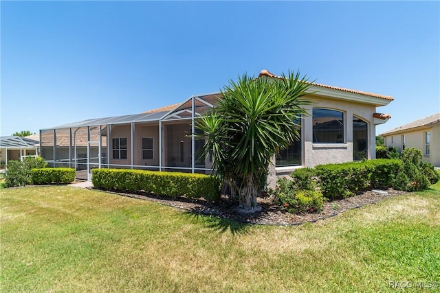 rear view of property featuring a yard, stucco siding, and a lanai