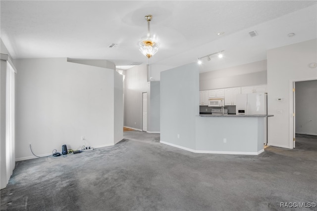 unfurnished living room featuring carpet floors, rail lighting, and lofted ceiling