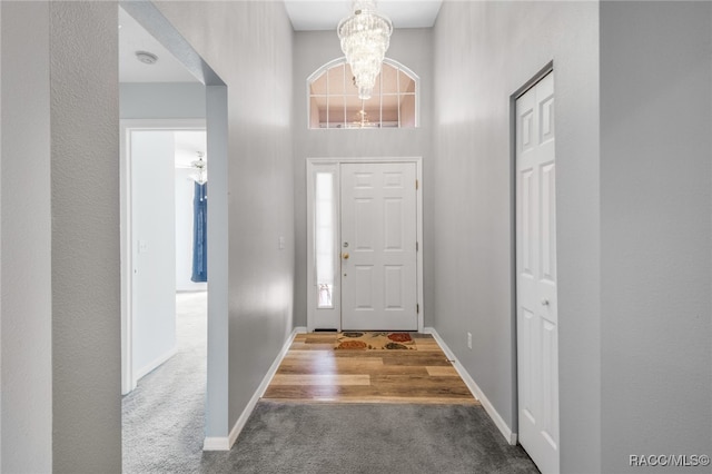 carpeted entrance foyer with a high ceiling and an inviting chandelier