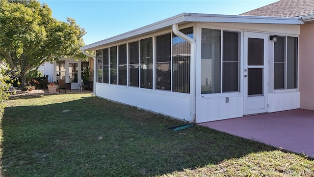 view of side of home featuring a yard, a patio area, and a sunroom