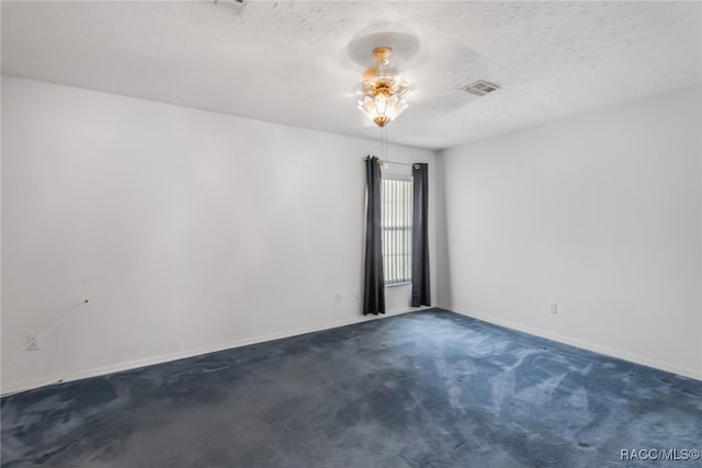 spare room with a textured ceiling and dark carpet