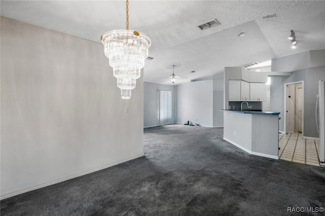 unfurnished living room with sink, a notable chandelier, a textured ceiling, vaulted ceiling, and dark carpet