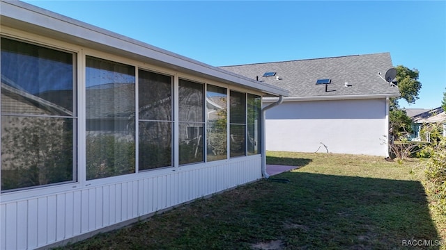 view of side of property with a sunroom and a yard