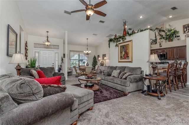 living room featuring ceiling fan with notable chandelier, a textured ceiling, and lofted ceiling