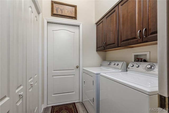 clothes washing area with washing machine and dryer, cabinets, and wood-type flooring