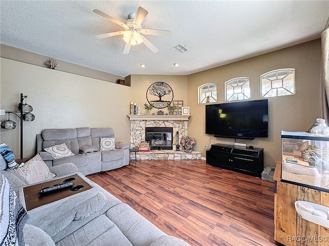 living room with ceiling fan, a fireplace, a textured ceiling, and hardwood / wood-style flooring