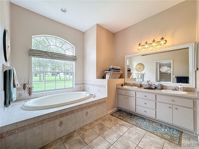 bathroom with tile patterned flooring, vanity, and tiled bath