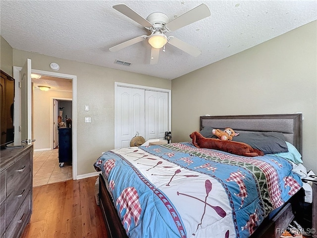 bedroom with a textured ceiling, hardwood / wood-style flooring, a closet, and ceiling fan