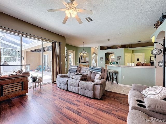 living room featuring hardwood / wood-style floors, a textured ceiling, and ceiling fan