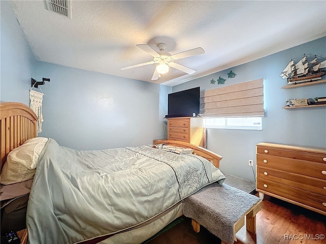 bedroom featuring a textured ceiling, ceiling fan, and dark wood-type flooring