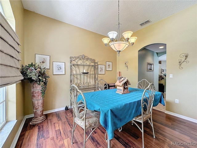 dining space with a chandelier, a textured ceiling, and hardwood / wood-style flooring