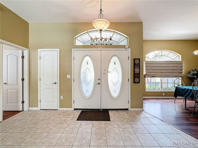 foyer featuring a chandelier, a textured ceiling, and light wood-type flooring