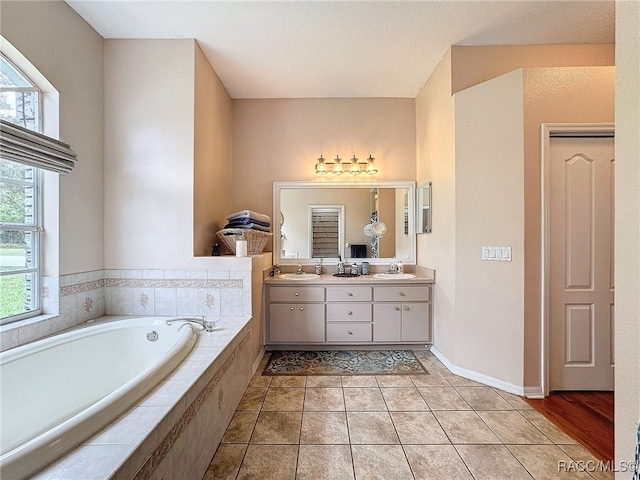 bathroom featuring tile patterned floors, vanity, and a relaxing tiled tub