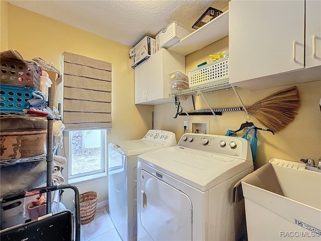 clothes washing area with cabinets, a textured ceiling, sink, separate washer and dryer, and light tile patterned flooring