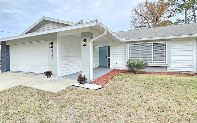 ranch-style house featuring a front yard, concrete driveway, roof with shingles, and an attached garage