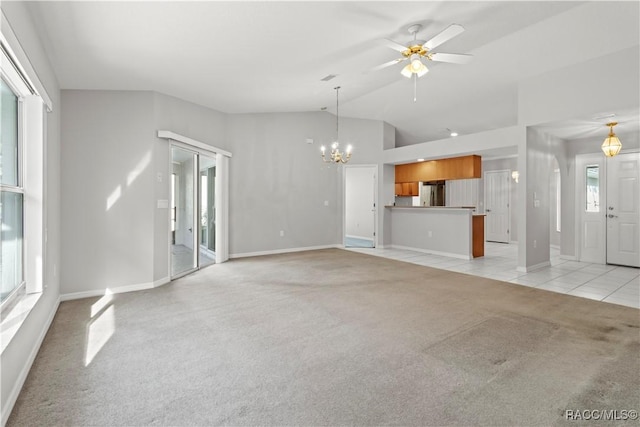 unfurnished living room featuring ceiling fan with notable chandelier, vaulted ceiling, and light carpet