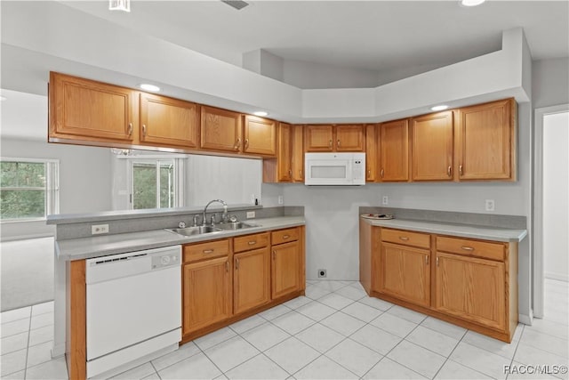 kitchen featuring white appliances, kitchen peninsula, sink, and light tile patterned floors