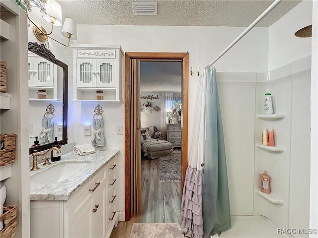 4101 E Gloria Dr, Hernando, FL 34442 - bathroom with vanity, wood finished floors, a shower with shower curtain, a textured ceiling, and ensuite bathroom