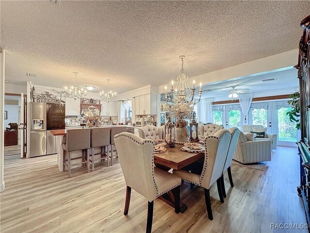 4101 E Gloria Dr, Hernando, FL 34442 - dining room with a chandelier, a textured ceiling, french doors, light wood-style flooring, and ceiling fan