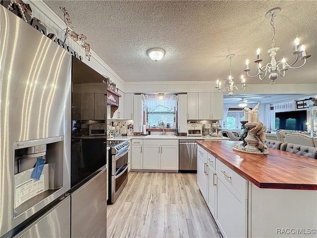 4101 E Gloria Dr, Hernando, FL 34442 - kitchen with butcher block counters, stainless steel appliances, a chandelier, a textured ceiling, and light wood-style floors