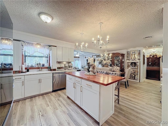 4101 E Gloria Dr, Hernando, FL 34442 - kitchen featuring stainless steel dishwasher, butcher block counters, a textured ceiling, a chandelier, and a kitchen bar