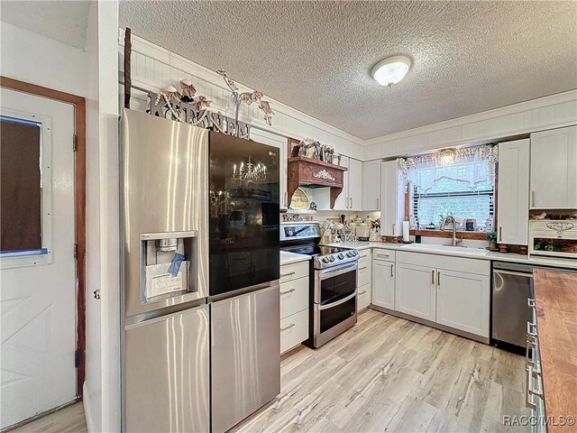 4101 E Gloria Dr, Hernando, FL 34442 - kitchen featuring appliances with stainless steel finishes, a textured ceiling, light wood-type flooring, white cabinets, and crown molding
