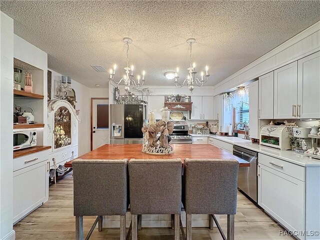 4101 E Gloria Dr, Hernando, FL 34442 - kitchen with stainless steel appliances, a chandelier, open shelves, a textured ceiling, and light wood-type flooring