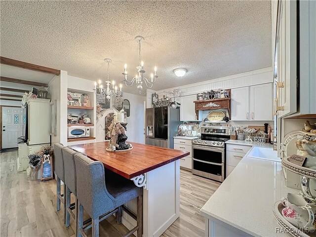 4101 E Gloria Dr, Hernando, FL 34442 - kitchen featuring appliances with stainless steel finishes, a chandelier, butcher block countertops, a textured ceiling, and light wood-type flooring