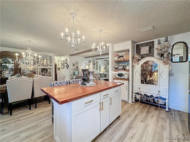 4101 E Gloria Dr, Hernando, FL 34442 - kitchen with butcher block counters, a chandelier, light wood-style flooring, white cabinets, and a textured ceiling
