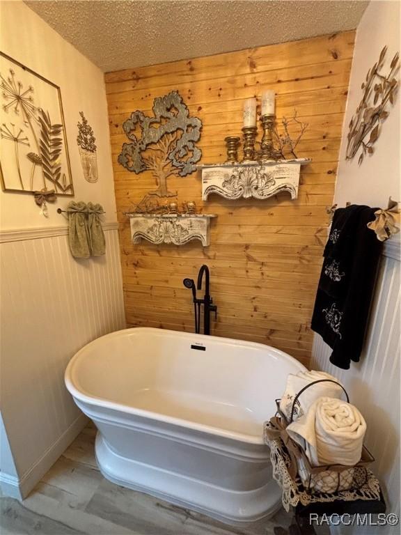 4101 E Gloria Dr, Hernando, FL 34442 - bathroom with wooden walls, a freestanding bath, a wainscoted wall, and a textured ceiling
