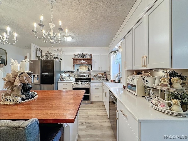 4101 E Gloria Dr, Hernando, FL 34442 - kitchen featuring stainless steel appliances, a textured ceiling, a chandelier, light wood-style floors, and white cabinetry
