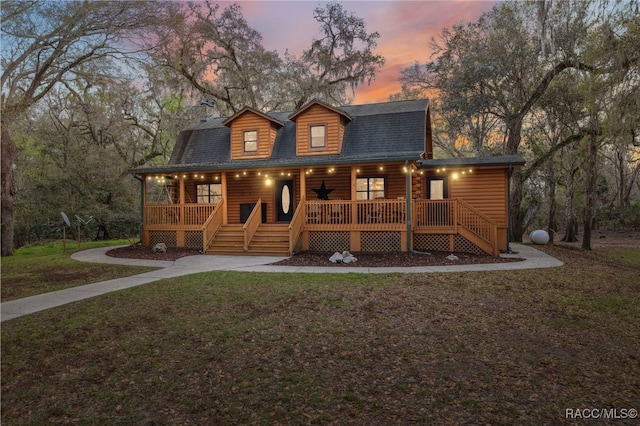 view of front facade featuring stairs, a porch, a lawn, and faux log siding