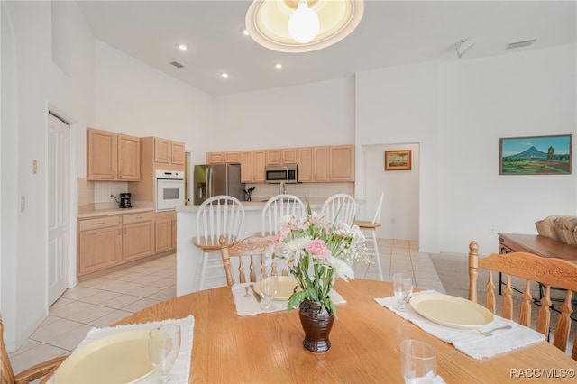 tiled dining area featuring a towering ceiling