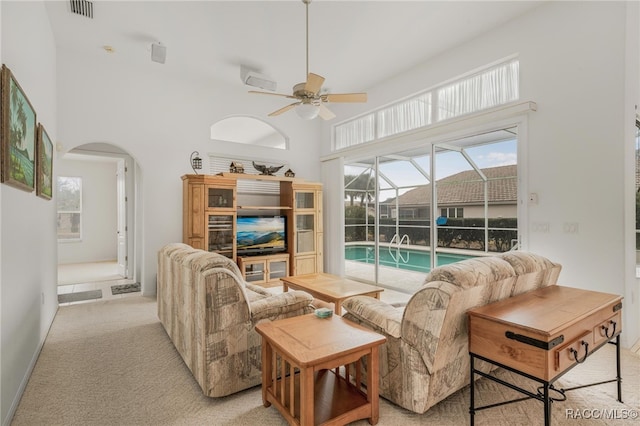 living room featuring light carpet, ceiling fan, and a high ceiling