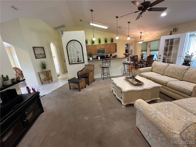 living area featuring visible vents, ceiling fan, arched walkways, light colored carpet, and vaulted ceiling