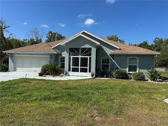 view of front of property with roof with shingles, an attached garage, concrete driveway, stucco siding, and a front yard