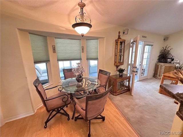dining area with a textured ceiling, baseboards, and wood finished floors