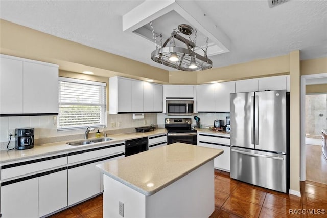 kitchen with sink, a center island, appliances with stainless steel finishes, white cabinets, and backsplash