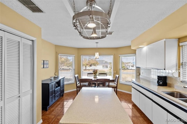 kitchen featuring blue cabinetry, sink, pendant lighting, decorative backsplash, and white cabinets