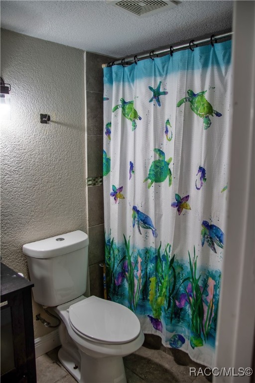 bathroom featuring vanity, a textured ceiling, toilet, and a shower with shower curtain