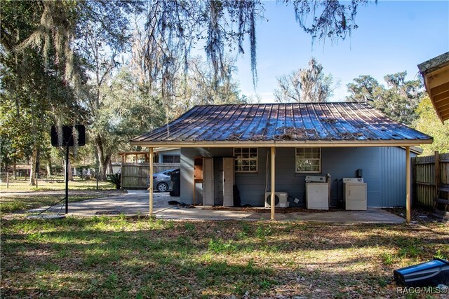 rear view of property featuring washing machine and clothes dryer, ac unit, and a yard