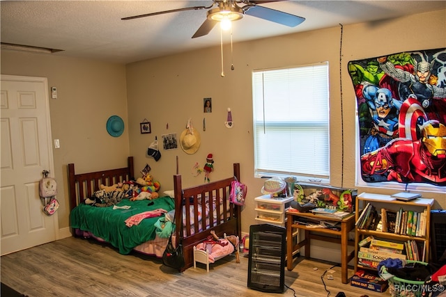 bedroom featuring ceiling fan, wood-type flooring, and a textured ceiling