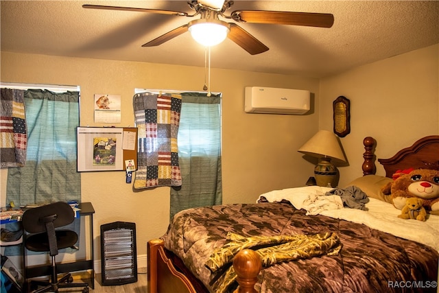 bedroom featuring a wall unit AC, ceiling fan, wood-type flooring, and a textured ceiling