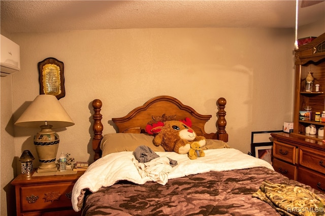 bedroom with a textured ceiling and a wall unit AC