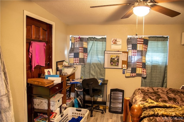 bedroom with ceiling fan, light hardwood / wood-style floors, and a textured ceiling