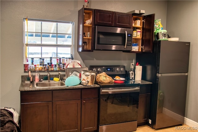 kitchen with dark brown cabinetry, stone counters, sink, and stainless steel appliances