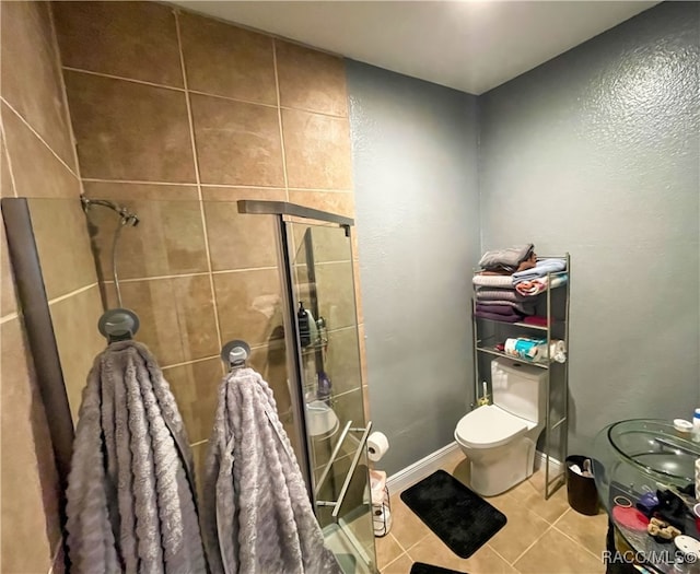 bathroom featuring tile patterned floors, toilet, and an enclosed shower