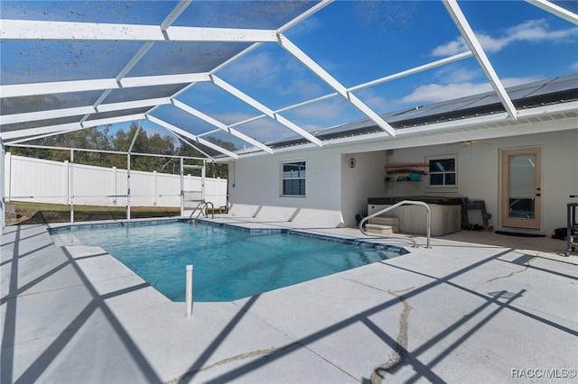 view of swimming pool featuring glass enclosure, a jacuzzi, fence, a fenced in pool, and a patio area