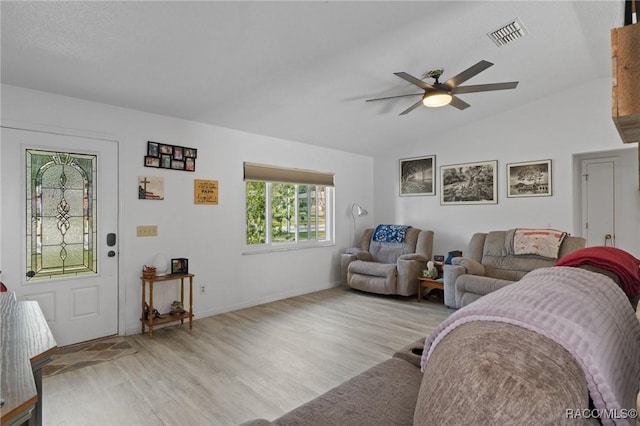 living area featuring light wood finished floors, visible vents, a ceiling fan, vaulted ceiling, and baseboards