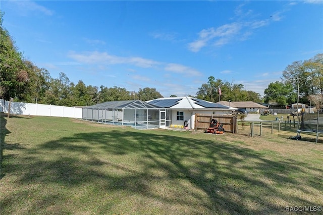 back of property with a yard, a fenced backyard, a fenced in pool, and roof mounted solar panels